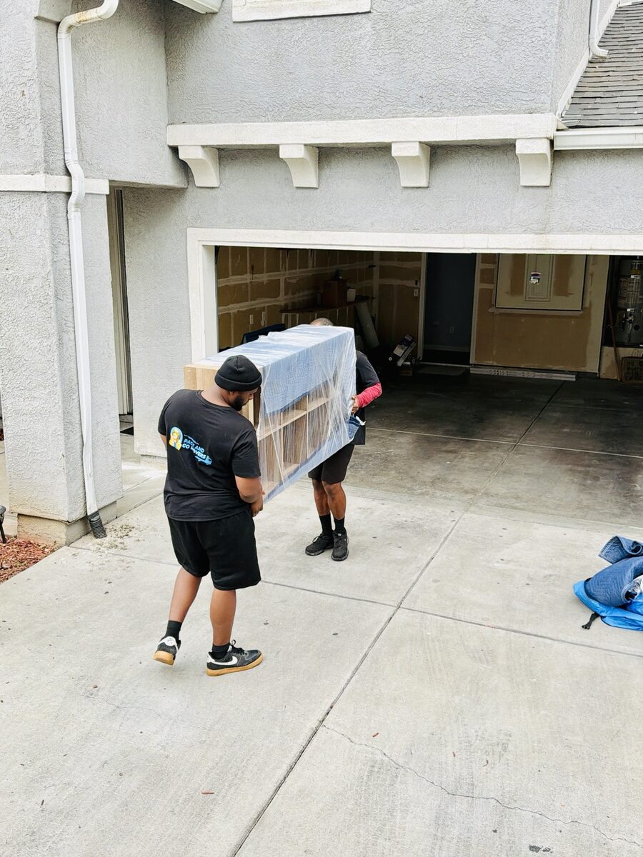 Two Pack And Go movers carrying professionally wrapped furniture from a Fresno home